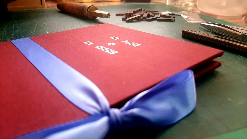 Portfolio slipcase tied with ribbon, bookbinders tools in background
