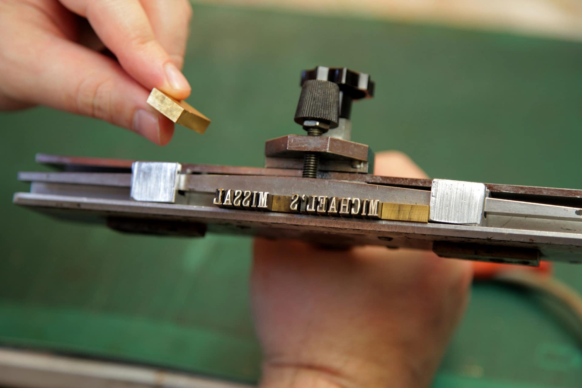 hands setting brass type which reads Michael's Missal for Children's Missal spine