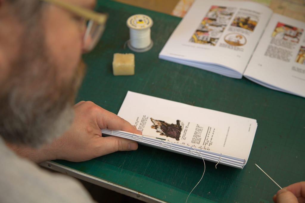 Sewing sections of the My Catholic Library Children's Missal by hand