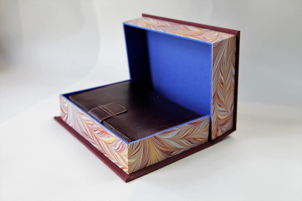 Clamshell box half open revealing leather book inside