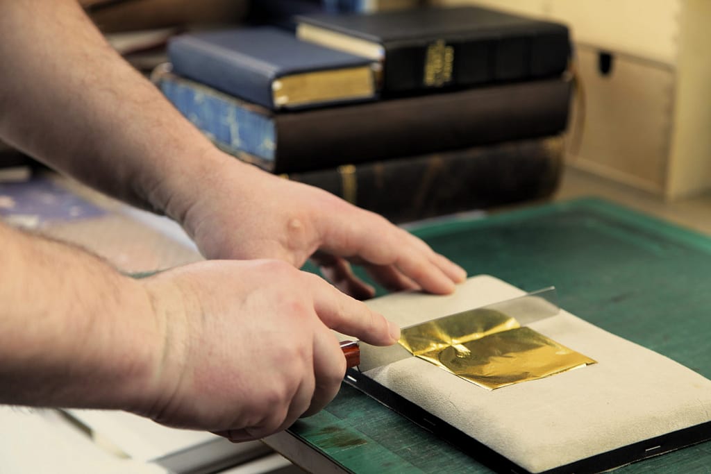 cutting gold leaf on a gilding cushion
