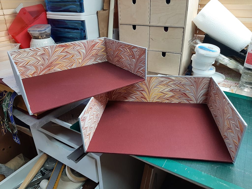 Inside of a clamshell book box lined with marble papers for a Traditional Latin Mass book